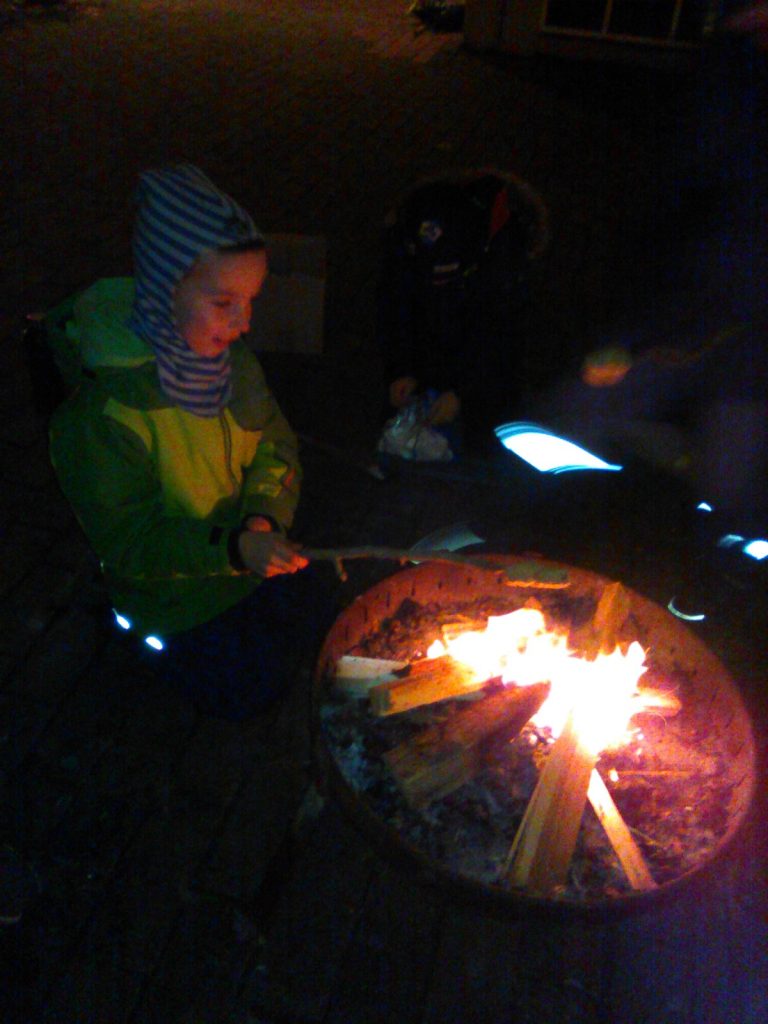 Ein Junge sitzt im halbdunkeln neben dem Lagerfeuer.