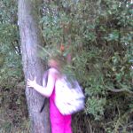 Ein Mädchen holt etwas aus einem Busch hervor