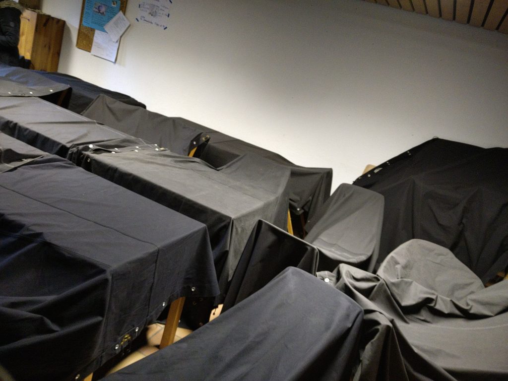 schwarze Zeltplanen liegen Quer über Tischen und Stühlen