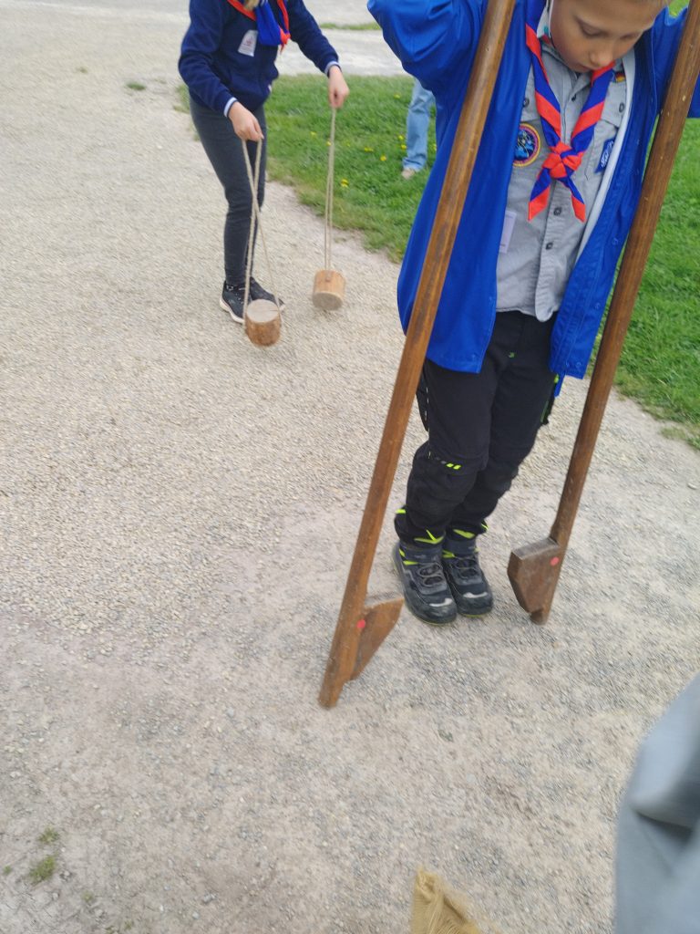 Ein Junge stiegt mit konzentriertem Gesicht auf Stelzen.