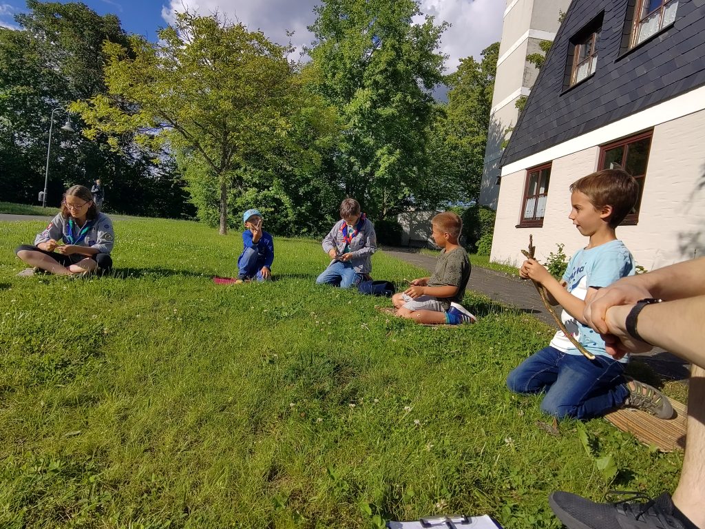 Vier Jungen sitzen in der Sonne auf der Wiese und schnitzten.